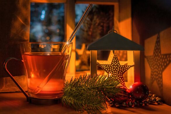 Házi karácsonyi tea friss és szárított kerti fűszernövényekkel egy ünnepi bögrében.