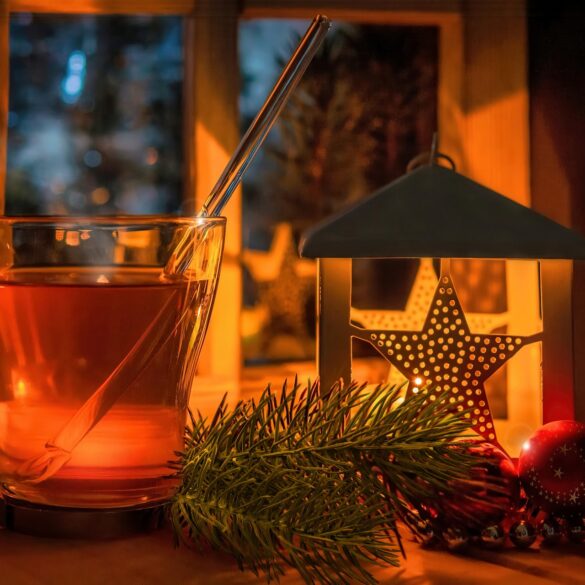 Házi karácsonyi tea friss és szárított kerti fűszernövényekkel egy ünnepi bögrében.